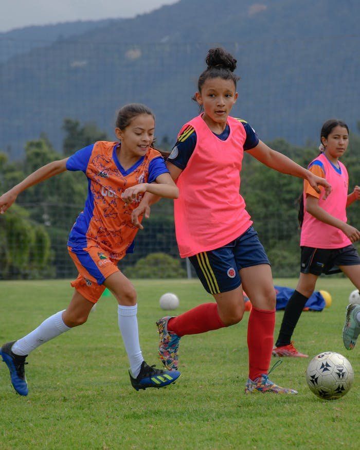 Young girls enthusiastically playing soccer in a vibrant outdoor setting.